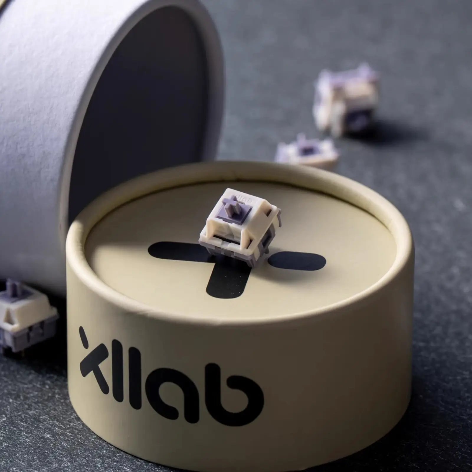 Round beige container with a cream and purple mechanical keyboard switch on top