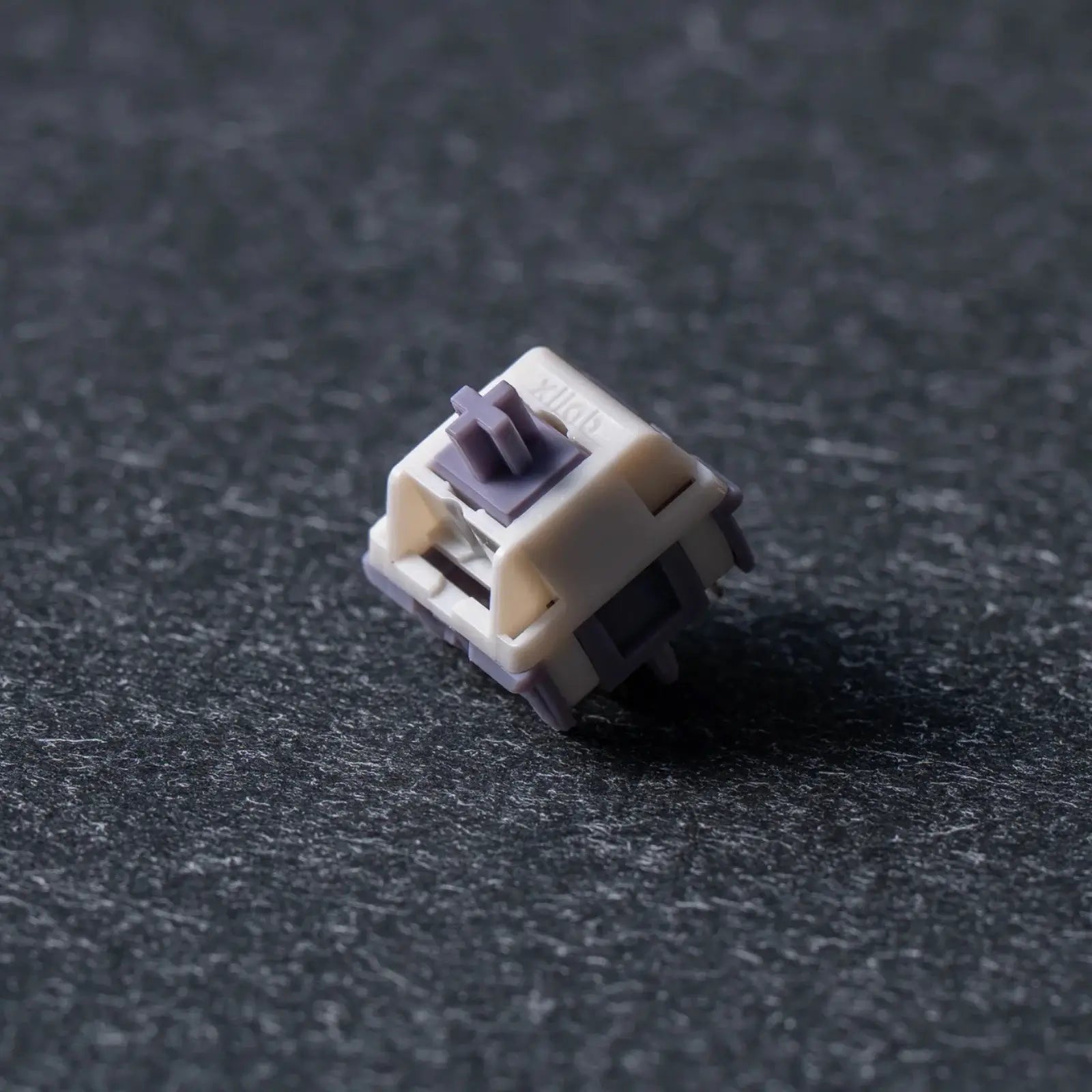 Mechanical keyboard switch on a dark textured surface