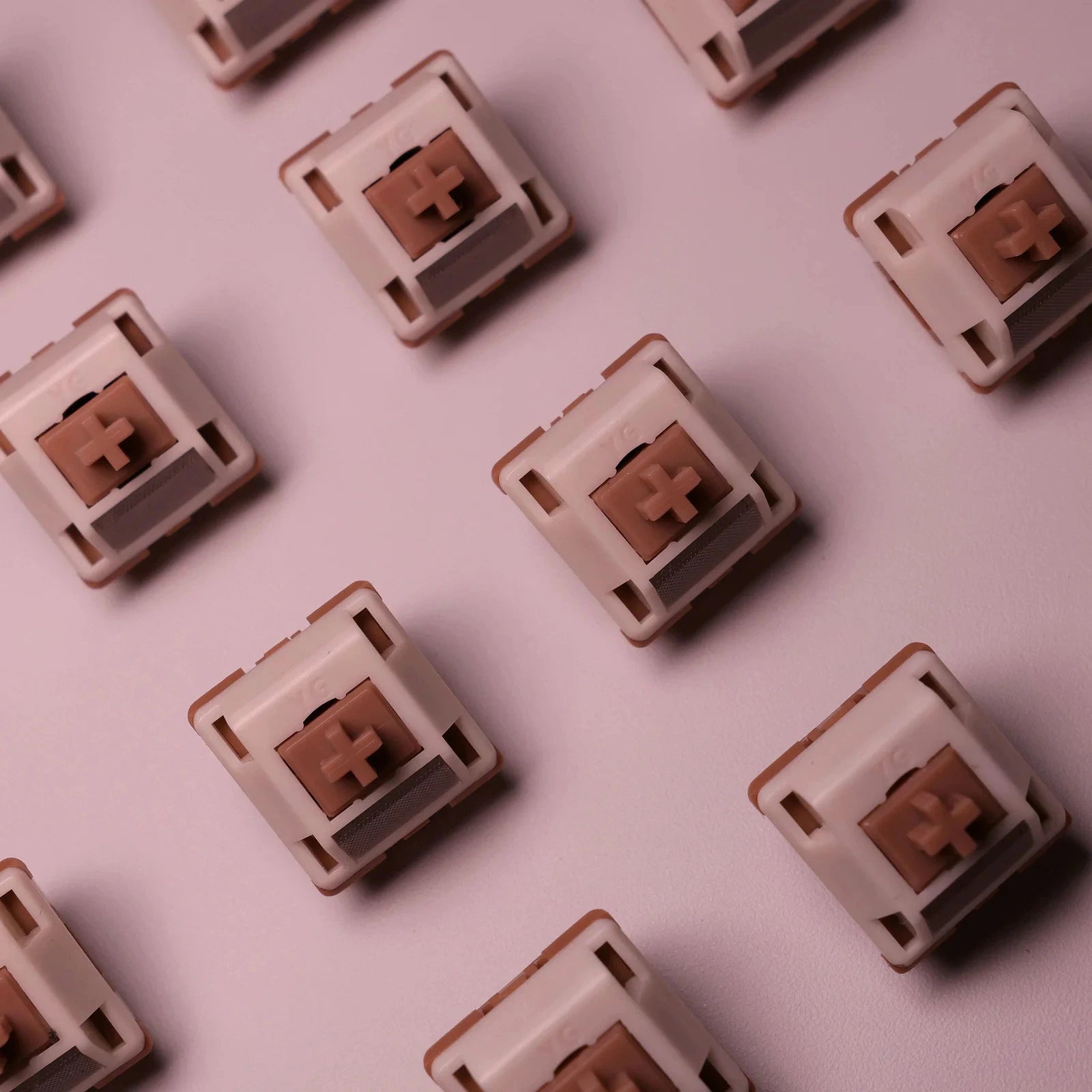 Pattern of beige and brown keyboard switches on a light pink background